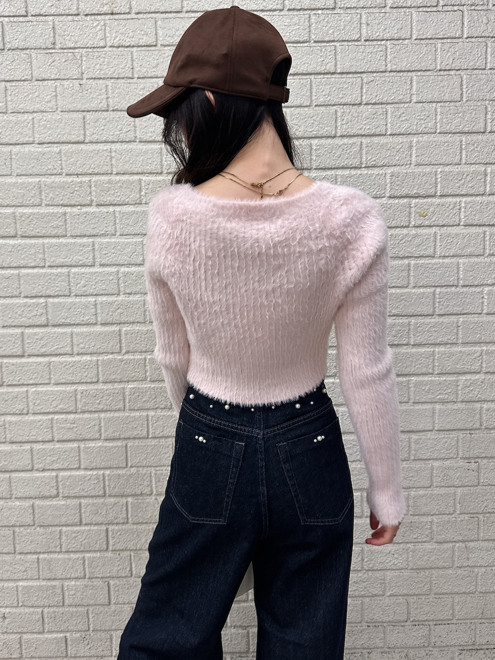 ピンク系のニット/セーター、ブルー系のデニムパンツ、ホワイト系のパンプスを着用したレディースの秋コーディネートの7枚目の写真