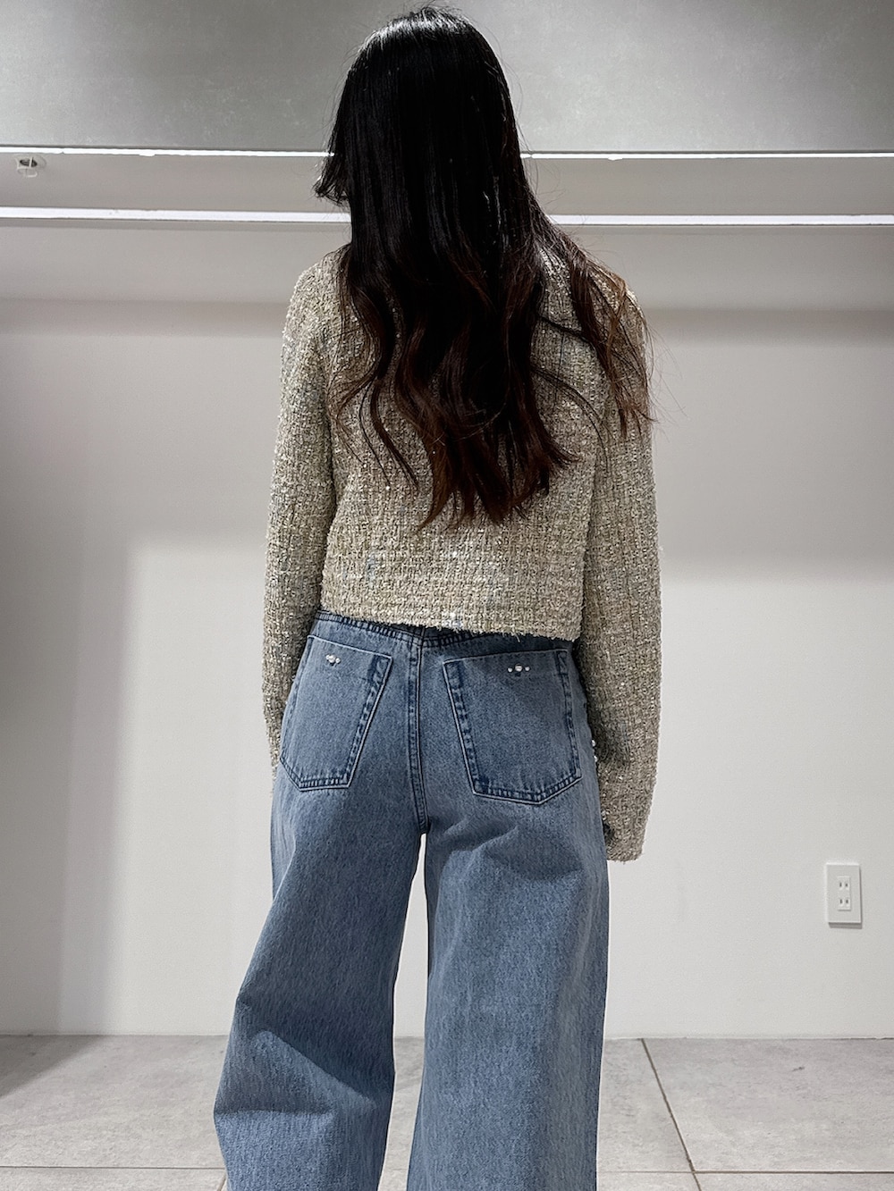 グリーン系のテーラードジャケット、ホワイト系のニット/セーター、ブルー系のデニムパンツを着用したレディースの春コーディネートの6枚目の写真