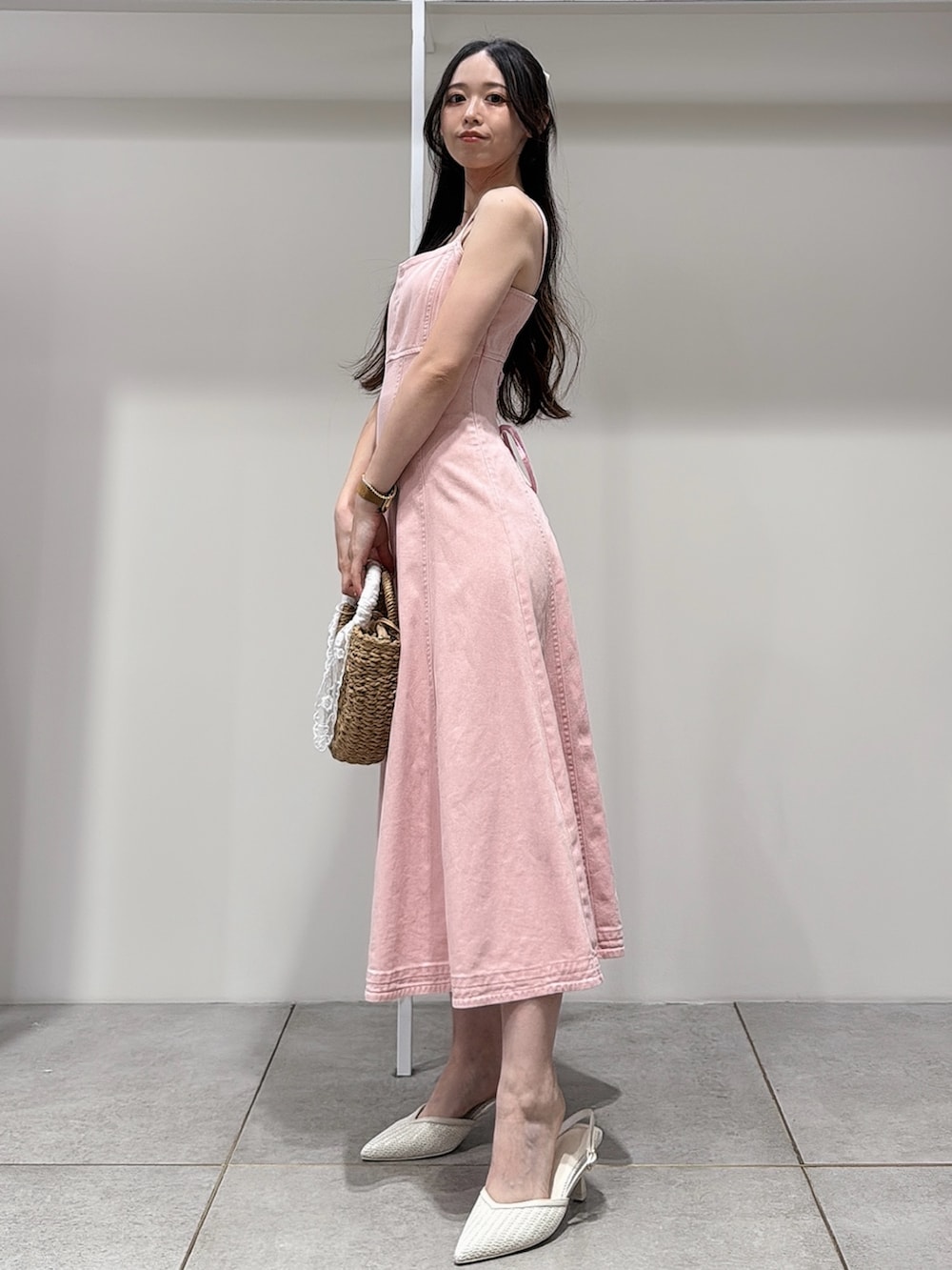 ピンク系のワンピース、ホワイト系のパンプス、ベージュ系のハンドバッグを着用したレディースの春コーディネートの2枚目の写真