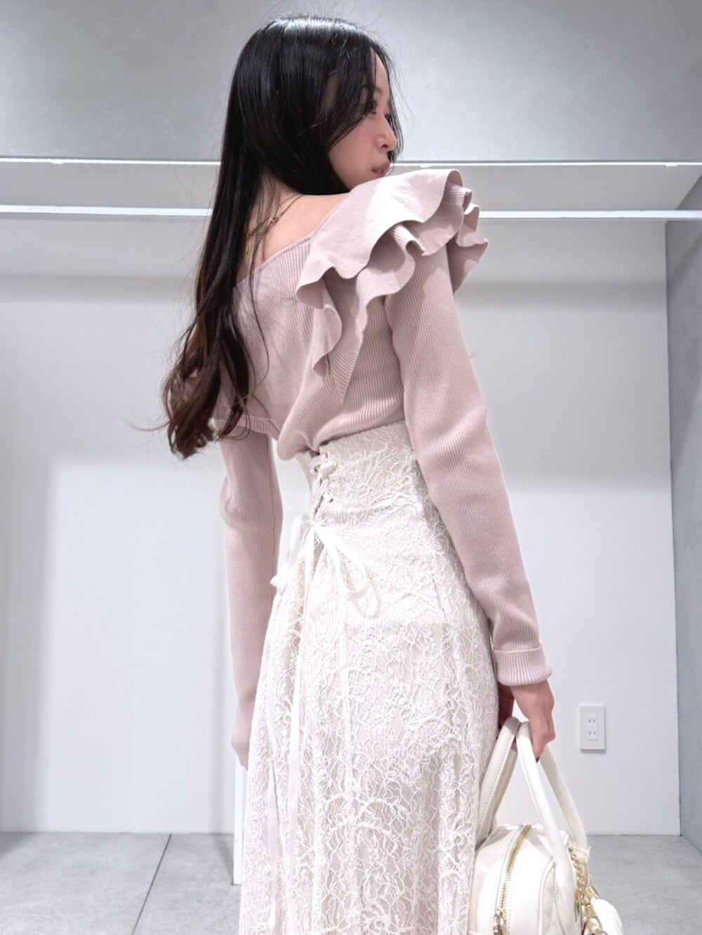 ホワイト系のハンドバッグ、ホワイト系のブーツ、ベージュ系のニット/セーターを着用したレディースの冬コーディネートの5枚目の写真