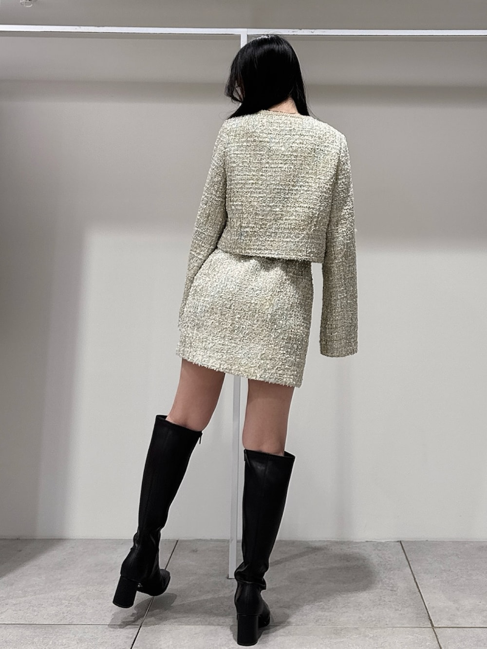 グリーン系のテーラードジャケット、グリーン系のスカート、ブラウン系のブーツを着用したレディースの春コーディネートの3枚目の写真