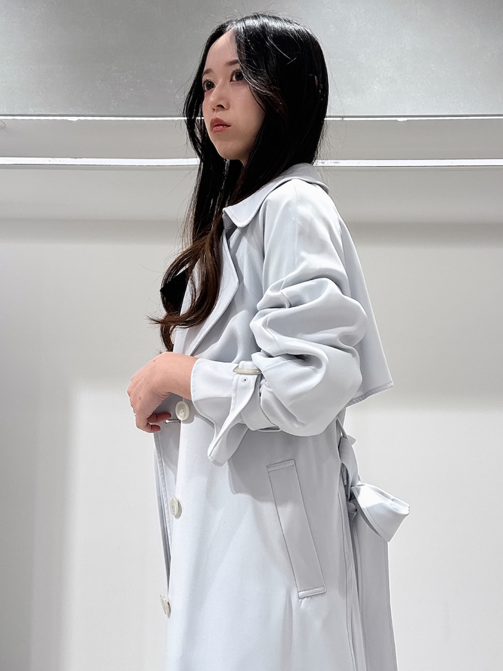 ブルー系のトレンチコート、ホワイト系のブーツ、ホワイト系のワンピースを着用したレディースの冬コーディネートの6枚目の写真