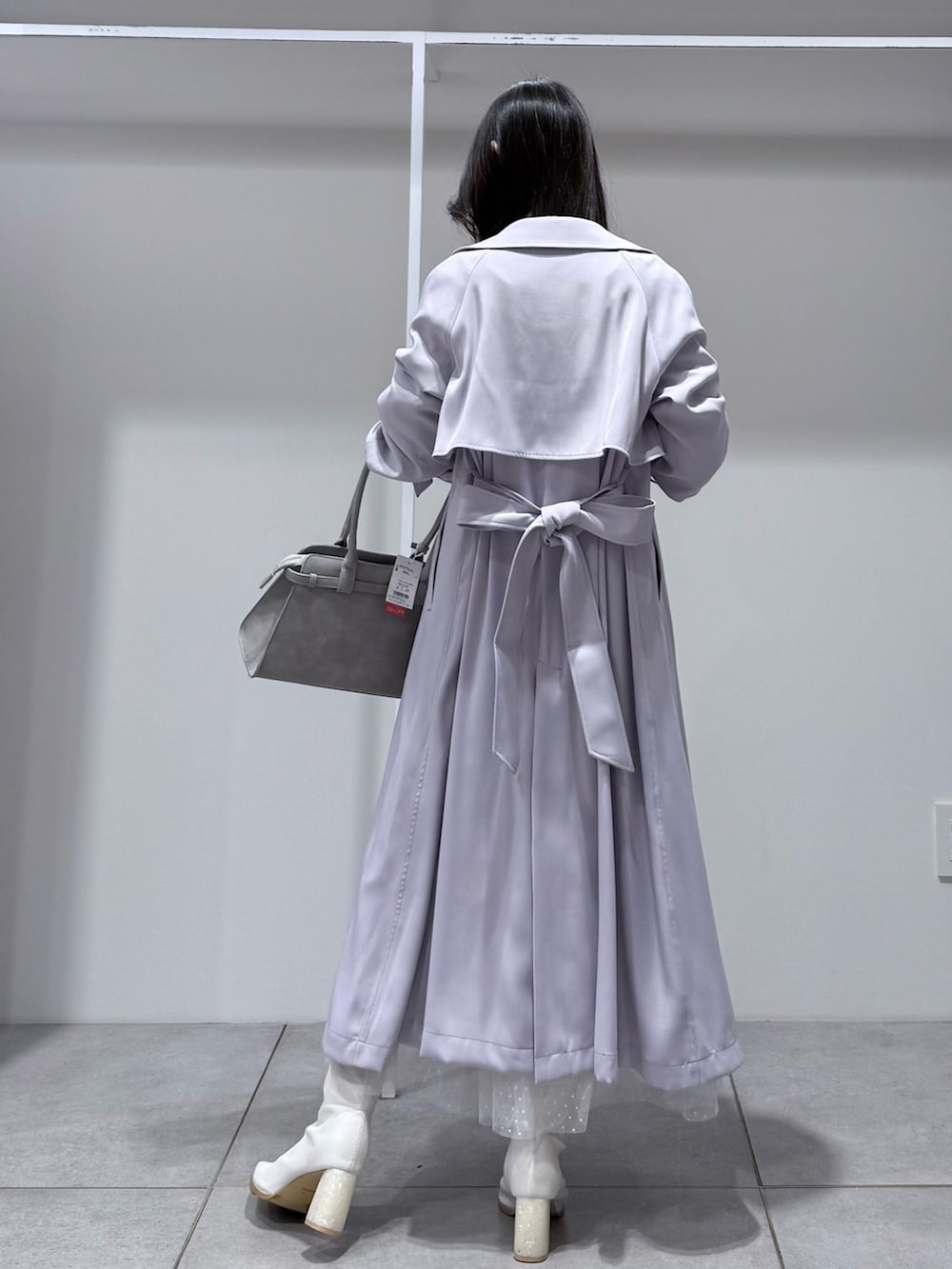 パープル系のトレンチコート、ホワイト系のワンピース、グレー系のハンドバッグを着用したレディースの冬コーディネートの3枚目の写真