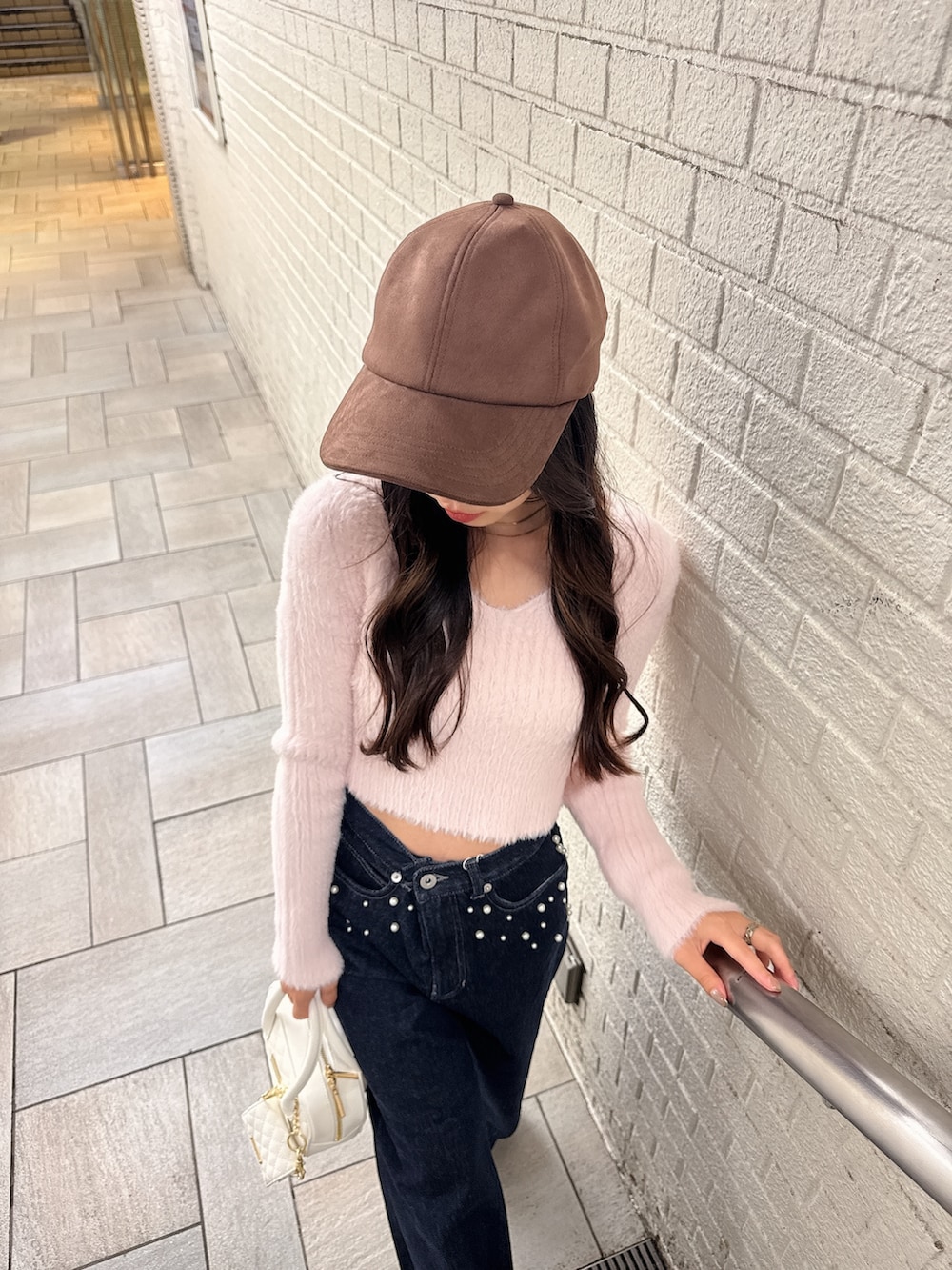 ピンク系のニット/セーター、ブルー系のデニムパンツ、ホワイト系のパンプスを着用したレディースの秋コーディネートの8枚目の写真