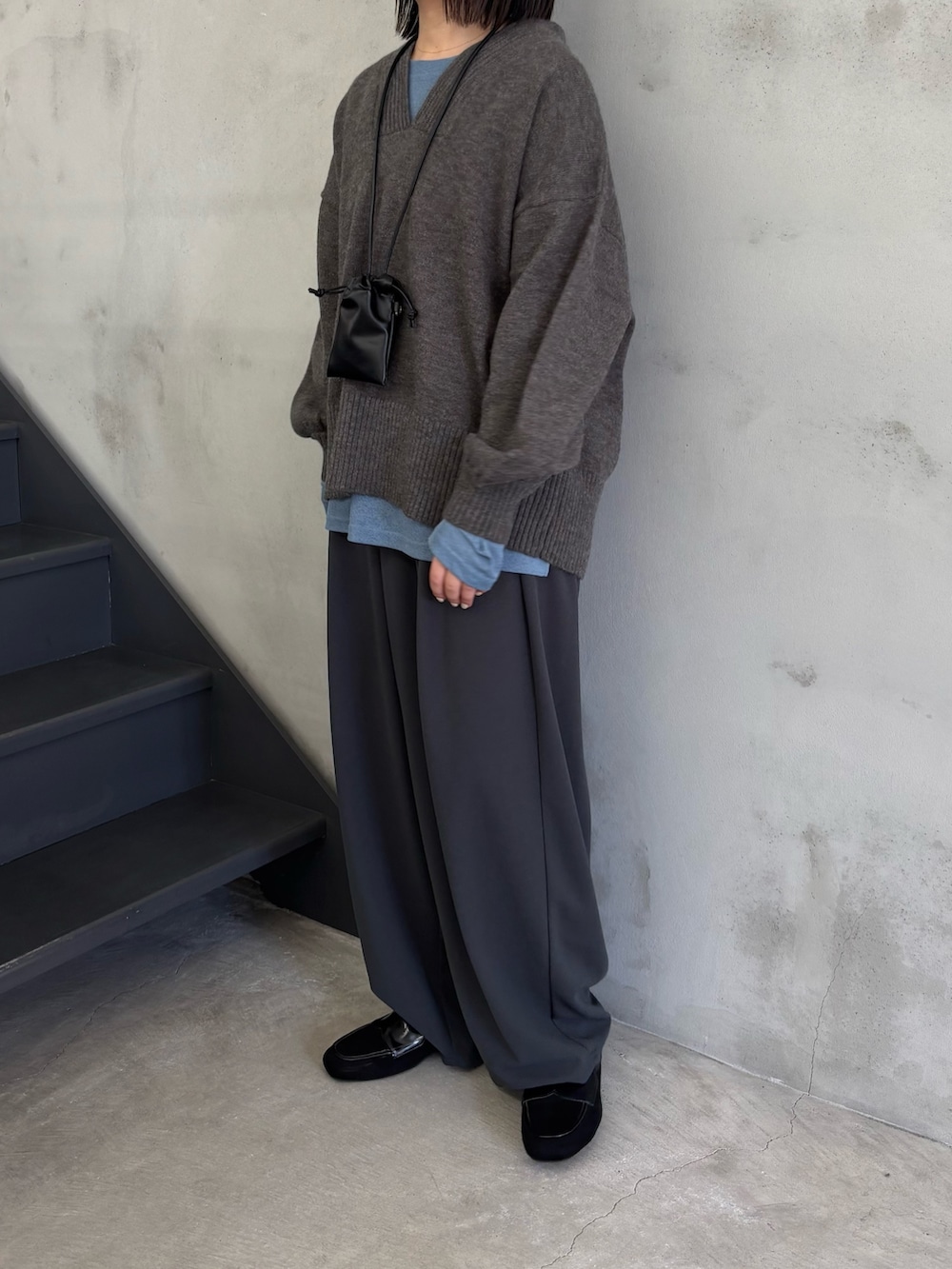 ブルー系のTシャツ/カットソー、グレー系のニット/セーター、グレー系のスラックスを着用したレディースの冬コーディネートの3枚目の写真