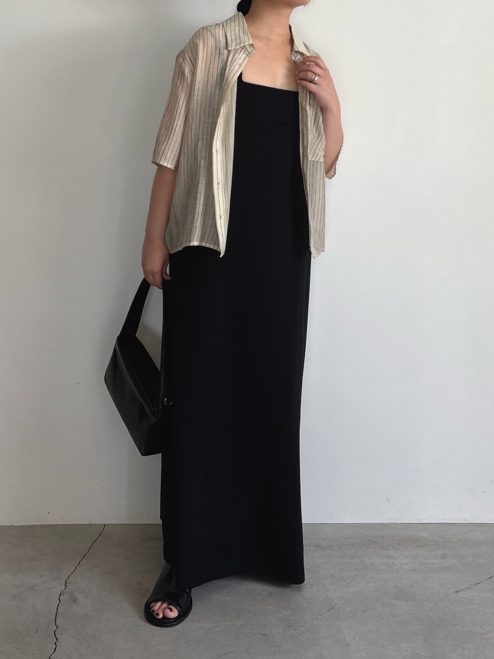 ブラック系のワンピース、ブラック系のショルダーバッグ、ブラック系のサンダルを着用したレディースの夏コーディネートの4枚目の写真