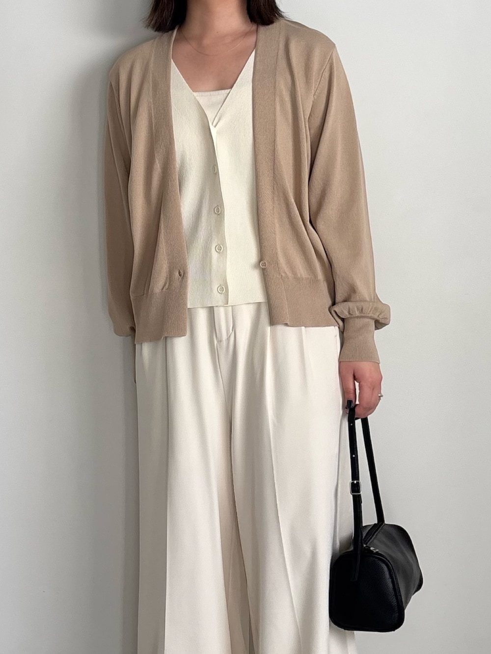 ベージュ系のカーディガン/ボレロ、ホワイト系のキャミソール、ホワイト系のスラックスを着用したレディースの冬コーディネートの5枚目の写真
