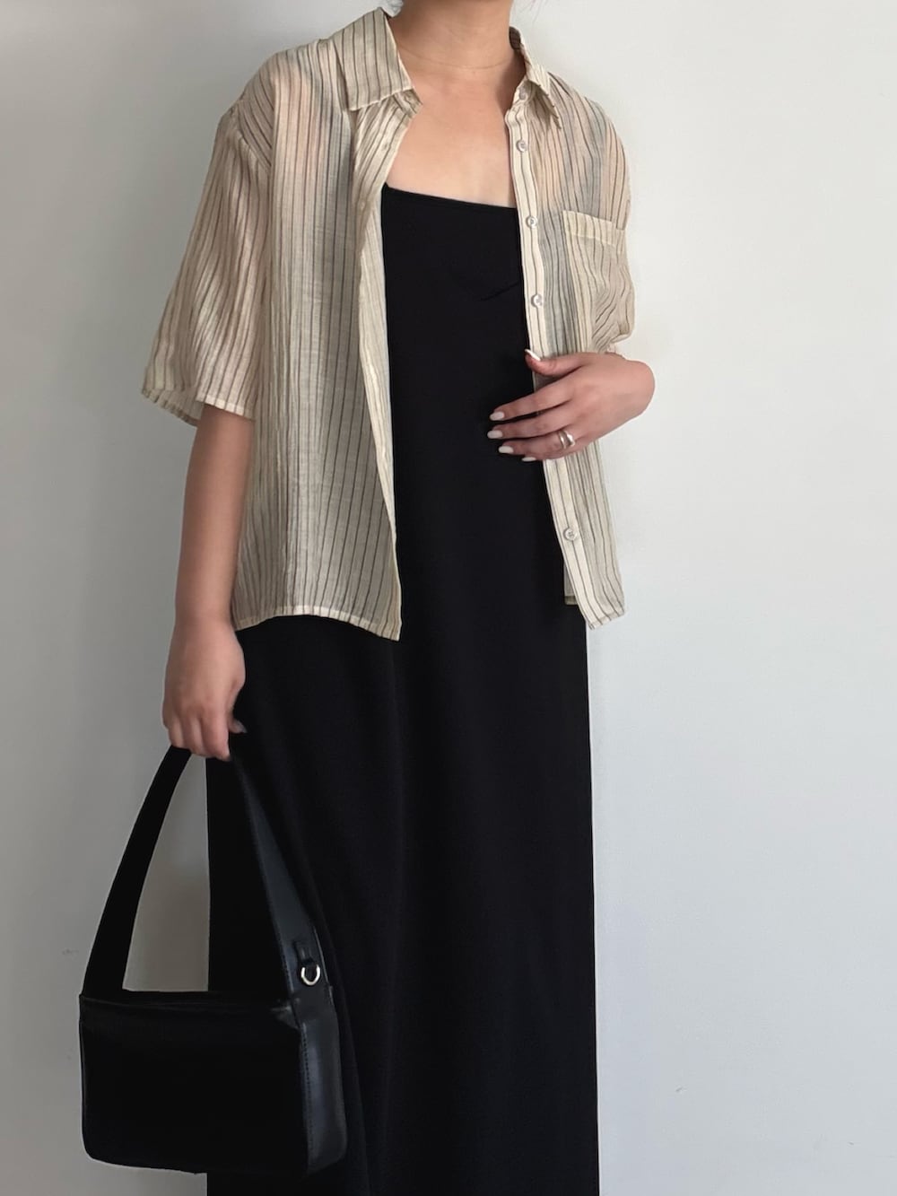 ブラック系のワンピース、ブラック系のショルダーバッグ、ブラック系のサンダルを着用したレディースの夏コーディネートの5枚目の写真