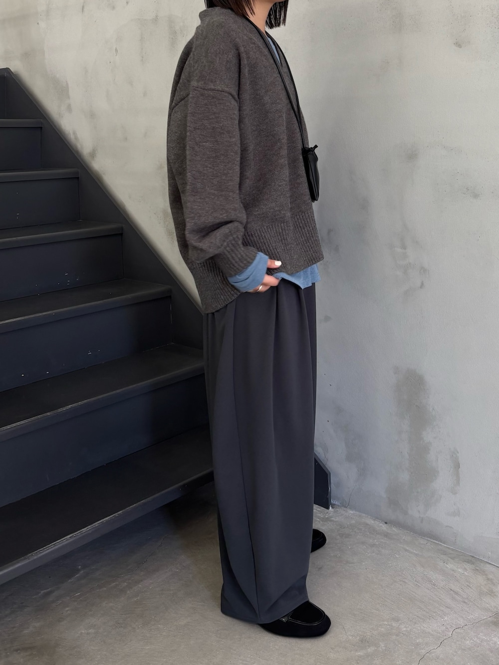 ブルー系のTシャツ/カットソー、グレー系のニット/セーター、グレー系のスラックスを着用したレディースの冬コーディネートの2枚目の写真