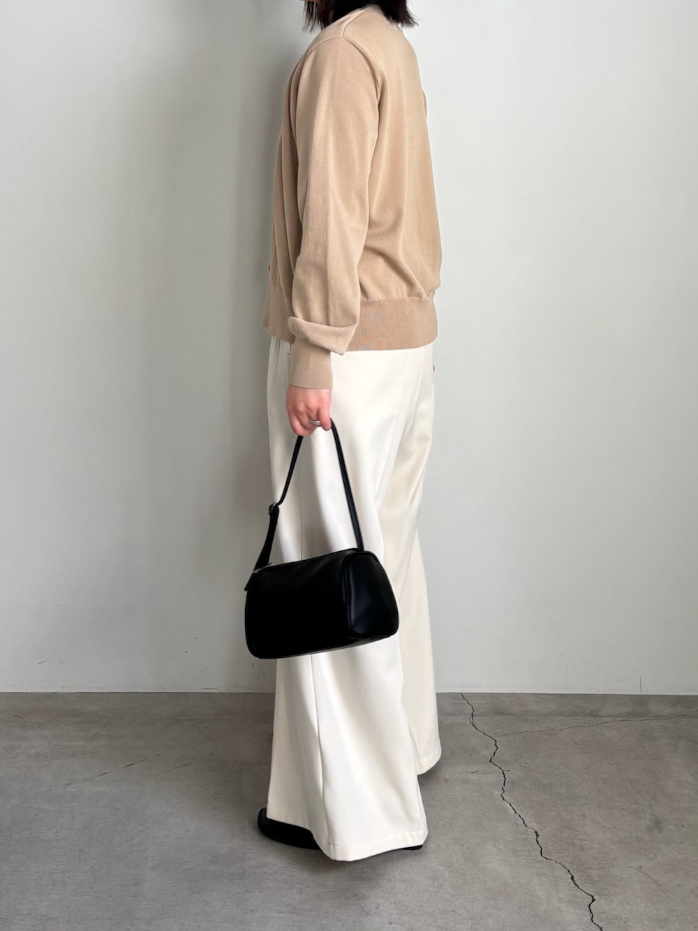 ベージュ系のカーディガン/ボレロ、ホワイト系のキャミソール、ホワイト系のスラックスを着用したレディースの冬コーディネートの2枚目の写真