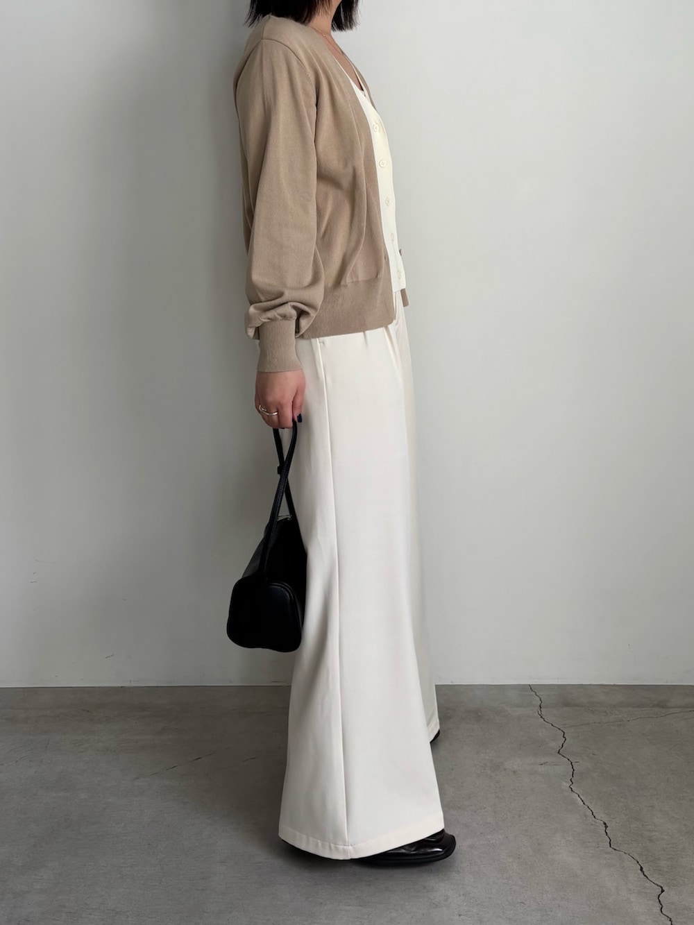 ベージュ系のカーディガン/ボレロ、ホワイト系のキャミソール、ホワイト系のスラックスを着用したレディースの冬コーディネートの4枚目の写真