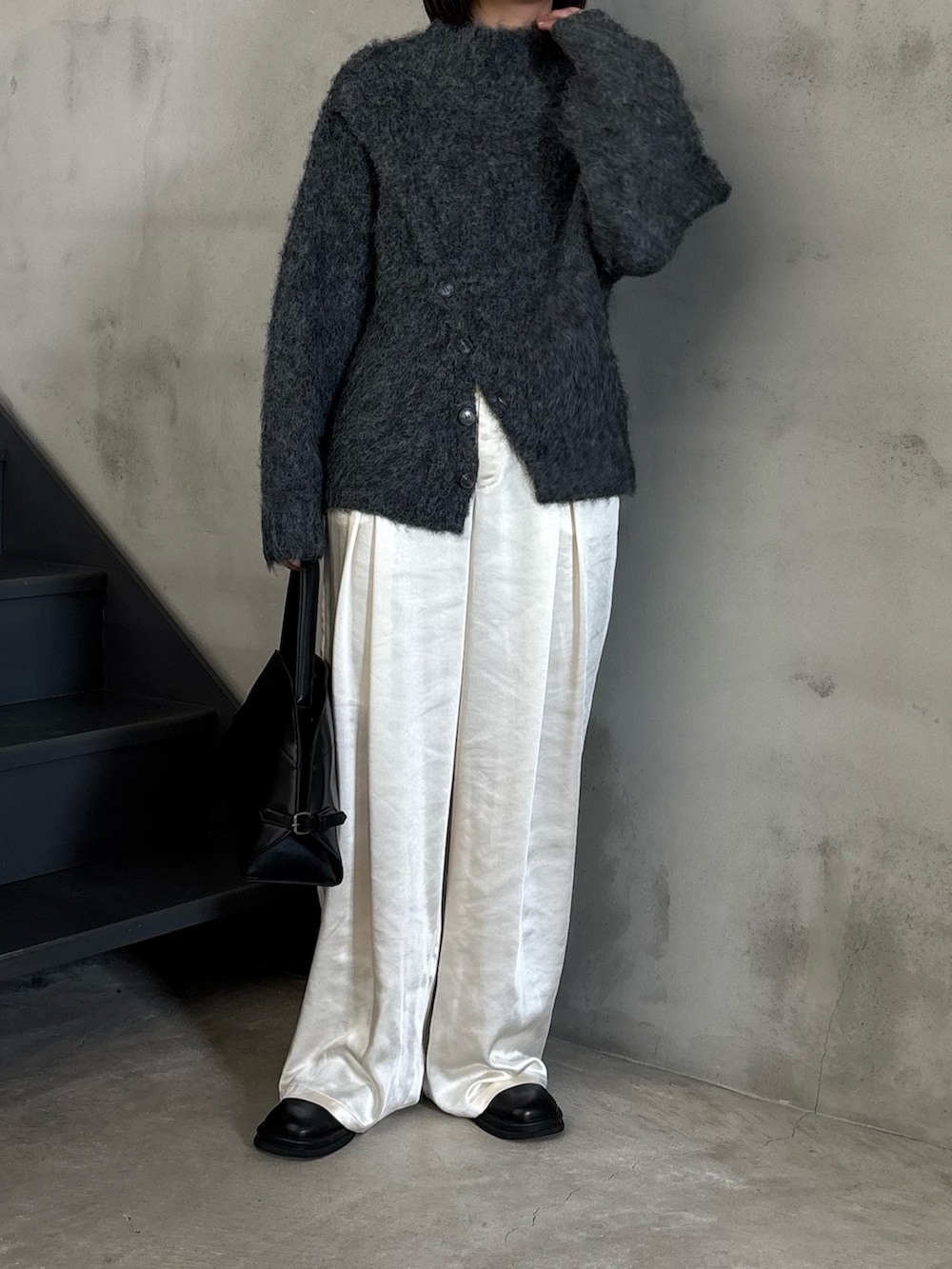 ブラック系のステンカラーコート、グレー系のニット/セーター、ブラック系のスリッポンを着用したレディースの秋コーディネートの2枚目の写真