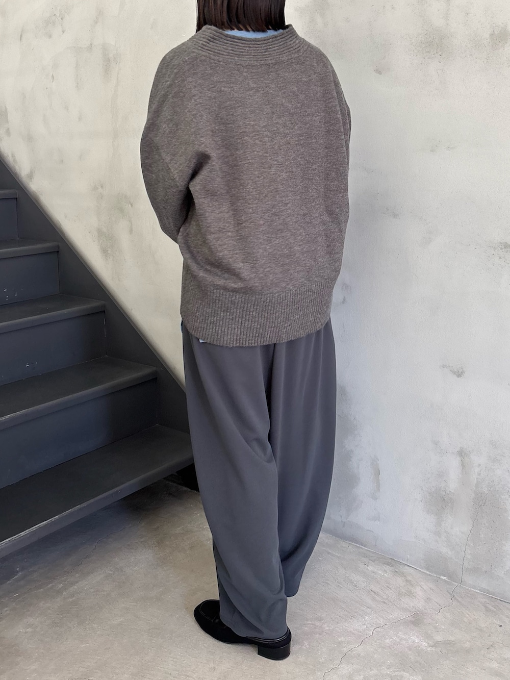 ブルー系のTシャツ/カットソー、グレー系のニット/セーター、グレー系のスラックスを着用したレディースの冬コーディネートの4枚目の写真