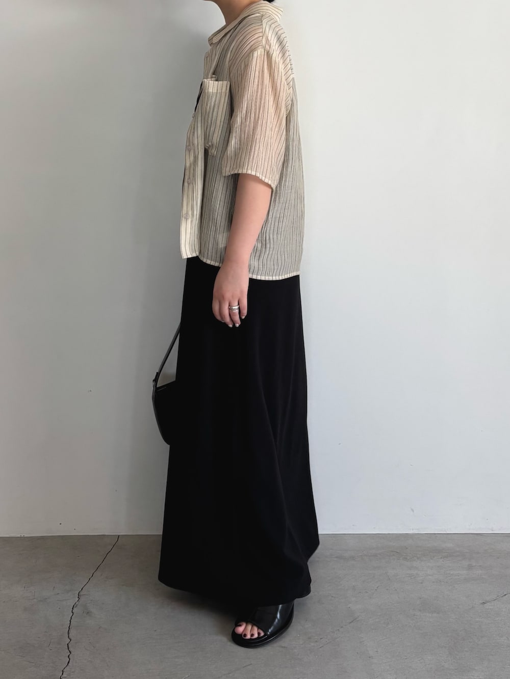 ブラック系のワンピース、ブラック系のショルダーバッグ、ブラック系のサンダルを着用したレディースの夏コーディネートの2枚目の写真