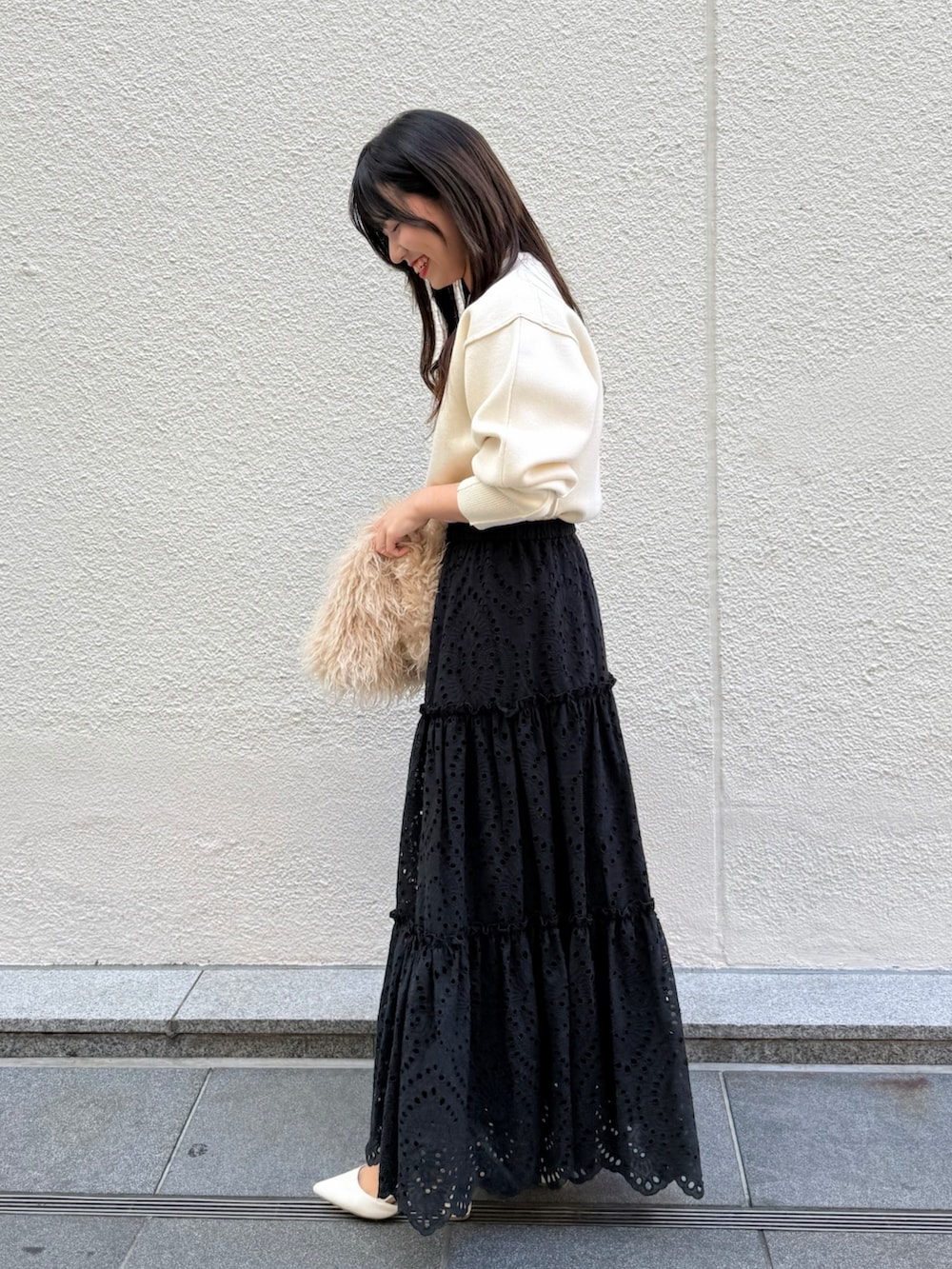 ブラック系のスカート、ベージュ系のショルダーバッグ、ホワイト系のニット/セーターを着用したレディースの秋コーディネートの4枚目の写真