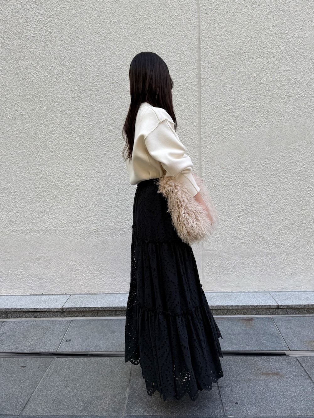 ブラック系のスカート、ベージュ系のショルダーバッグ、ホワイト系のニット/セーターを着用したレディースの秋コーディネートの2枚目の写真