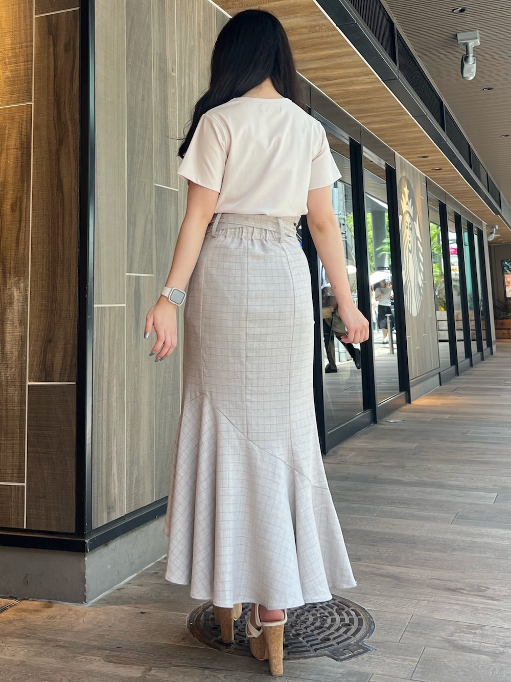 ベージュ系のスカート、グレー系のTシャツ/カットソー、ホワイト系のサンダルを着用したレディースの夏コーディネートの2枚目の写真