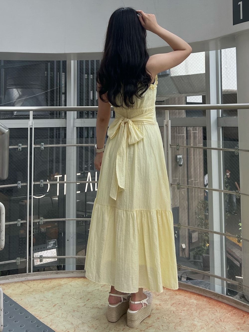 イエロー系のワンピース、ホワイト系のサンダルを着用したレディースの夏コーディネートの2枚目の写真