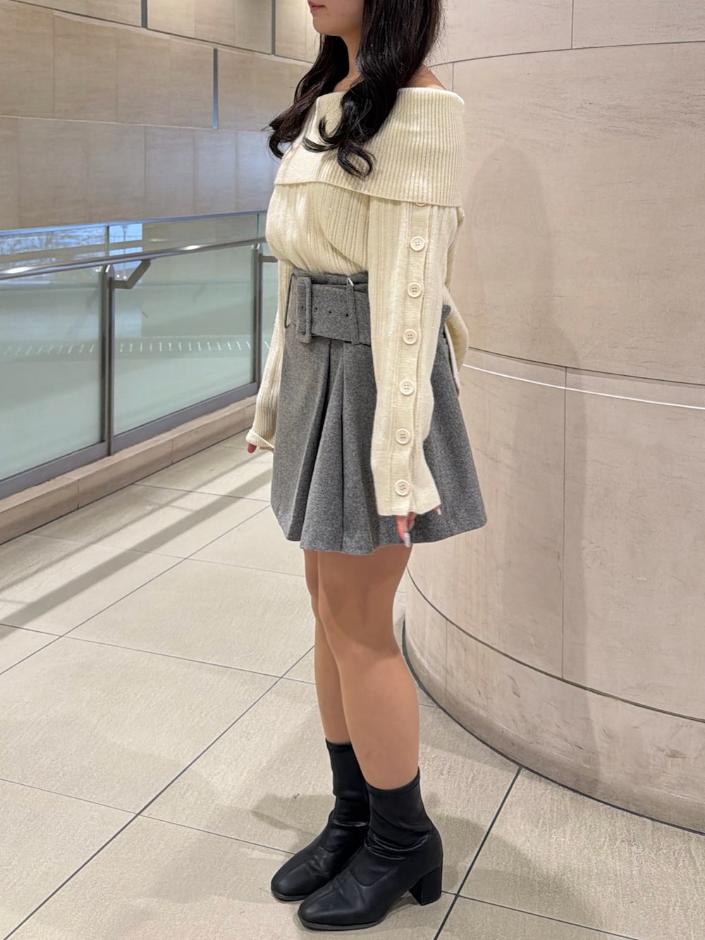 ホワイト系のニット/セーター、グレー系のスカート、ブラック系のブーツを着用したレディースの冬コーディネートの2枚目の写真