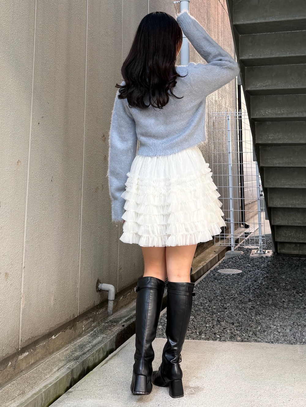 ブルー系のカーディガン/ボレロ、ホワイト系のスカート、ブラック系のブーツを着用したレディースの冬コーディネートの3枚目の写真
