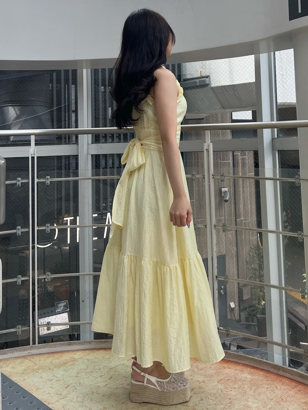 イエロー系のワンピース、ホワイト系のサンダルを着用したレディースの夏コーディネートの3枚目の写真