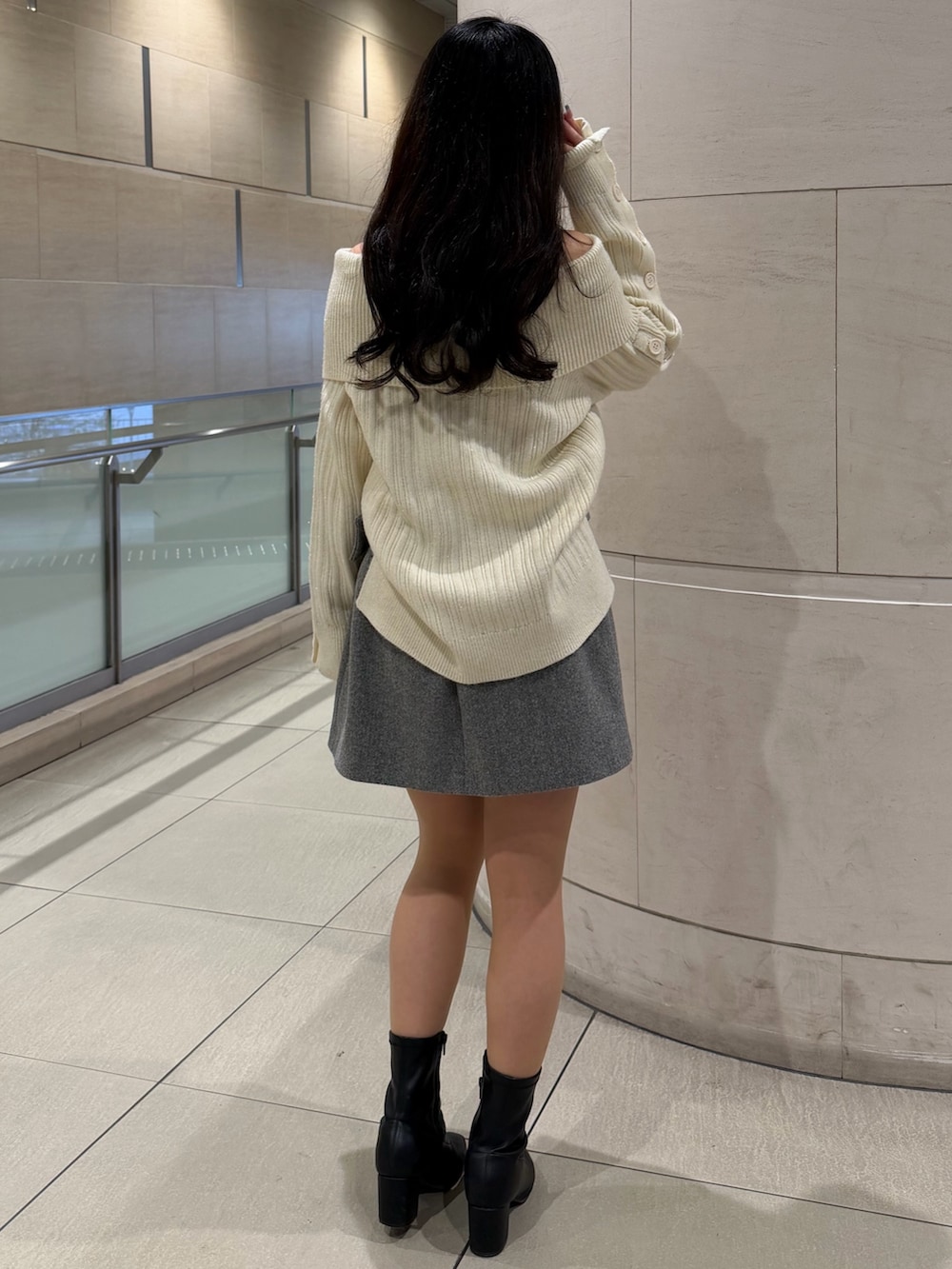 ホワイト系のニット/セーター、グレー系のスカート、ブラック系のブーツを着用したレディースの冬コーディネートの3枚目の写真