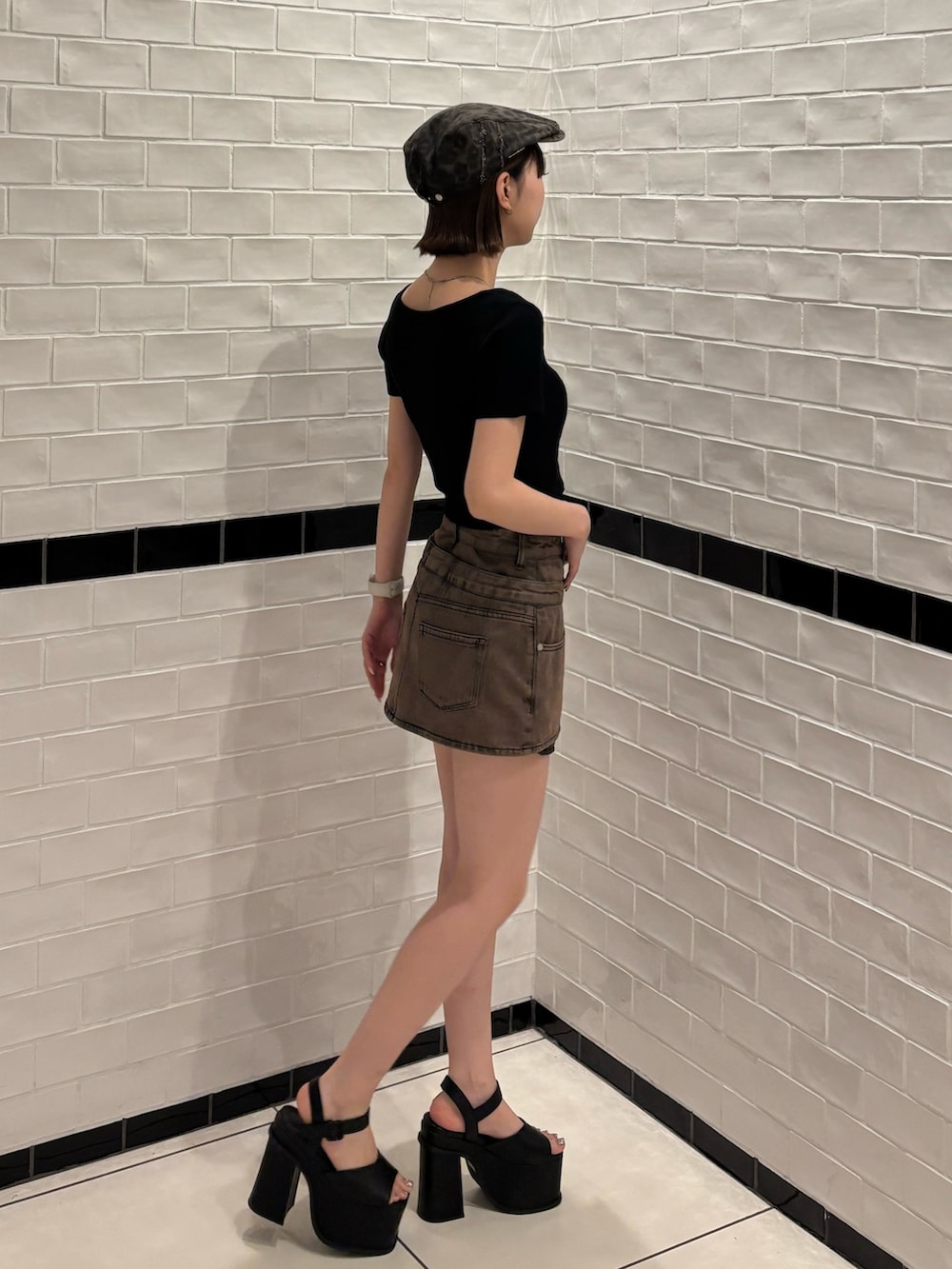 ブラック系のニット/セーター、ブラウン系のスカート、ブラック系のサンダルを着用したレディースの春コーディネートの3枚目の写真