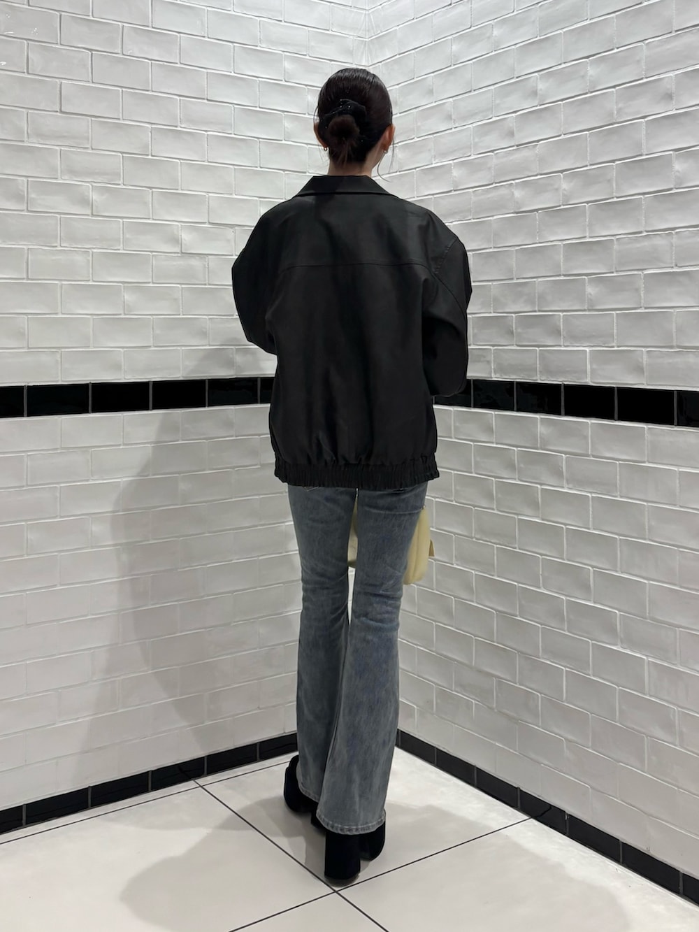 ブラック系のブルゾン、ブルー系のデニムパンツ、ブラック系のブーツを着用したレディースの秋コーディネートの3枚目の写真