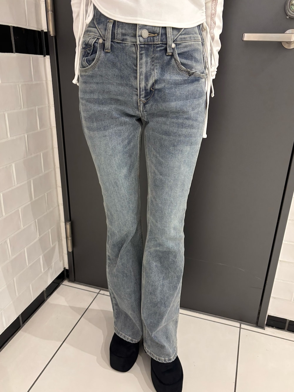 ブラック系のブルゾン、ブルー系のデニムパンツ、ブラック系のブーツを着用したレディースの秋コーディネートの5枚目の写真