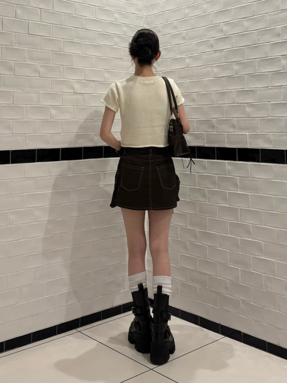 ブラウン系のスカート、ブラック系のブーツ、ホワイト系のニット/セーターを着用したレディースの夏コーディネートの3枚目の写真