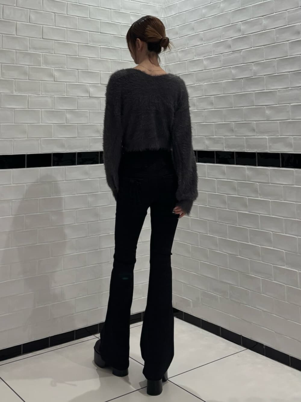 グレー系のニット/セーター、ブラック系のデニムパンツ、ブラック系のブーツを着用したレディースの秋コーディネートの3枚目の写真