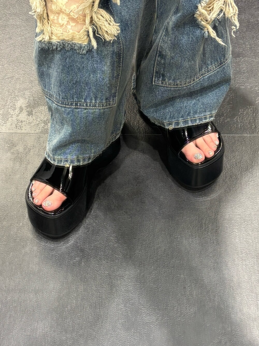 ブラック系のサンダル、ブラック系のニット/セーター、ブルー系のデニムパンツを着用したレディースの春コーディネートの6枚目の写真