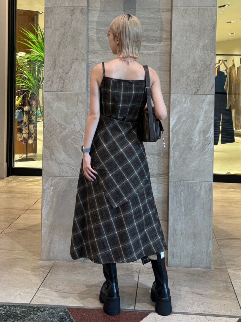 ブラウン系のハンドバッグ、グリーン系のワンピース、ブラック系のブーツを着用したレディースの夏コーディネートの4枚目の写真