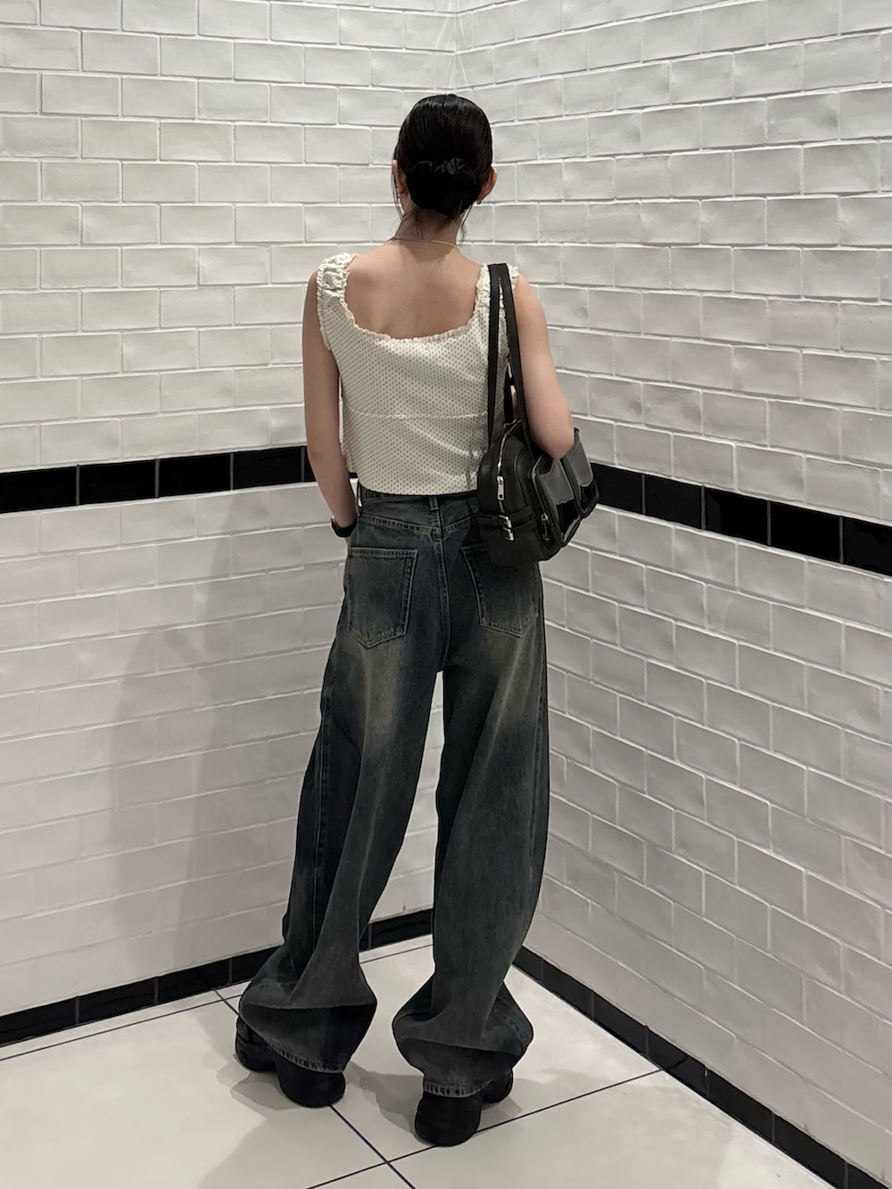 ホワイト系のタンクトップ、ブルー系のデニムパンツ、ブラック系のショルダーバッグを着用したレディースの夏コーディネートの3枚目の写真