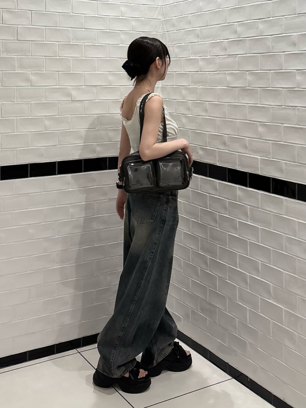 ホワイト系のタンクトップ、ブルー系のデニムパンツ、ブラック系のショルダーバッグを着用したレディースの夏コーディネートの2枚目の写真