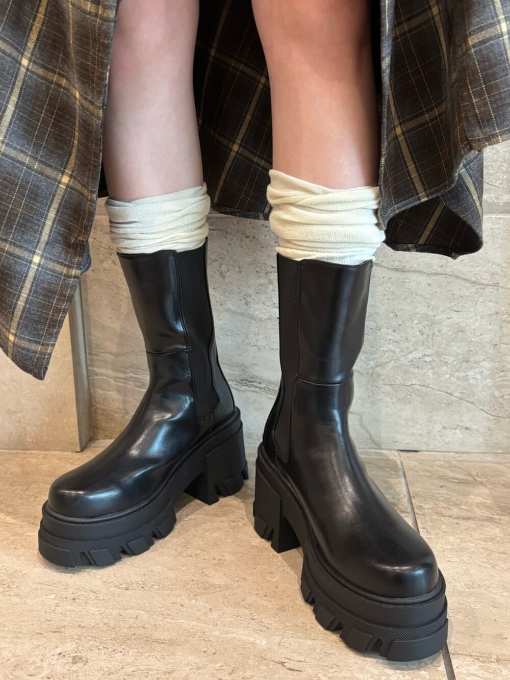 ブラウン系のハンドバッグ、グリーン系のワンピース、ブラック系のブーツを着用したレディースの夏コーディネートの6枚目の写真