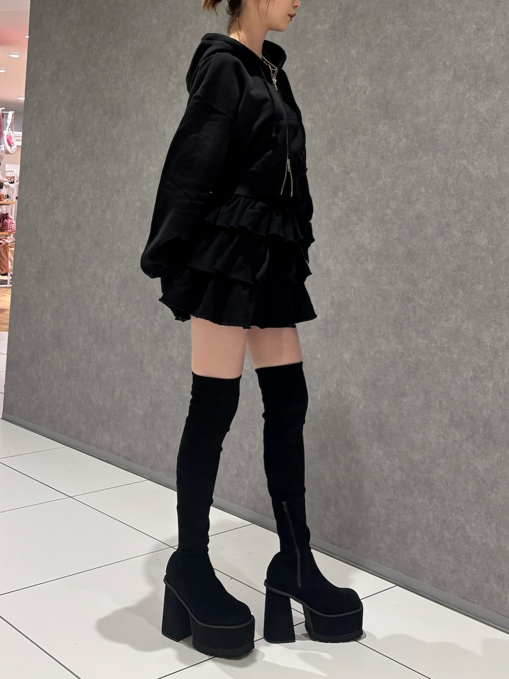 ブラック系のパーカー、ブラック系のスカート、ブラック系のブーツを着用したレディースの秋コーディネートの3枚目の写真