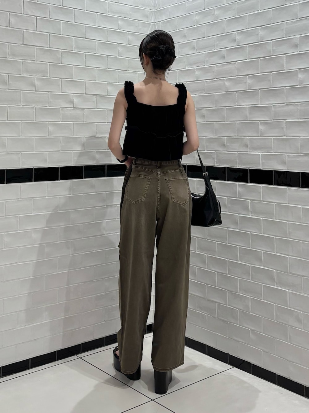 ブラック系のタンクトップ、ブラウン系のデニムパンツ、ブラック系のサンダルを着用したレディースの夏コーディネートの3枚目の写真
