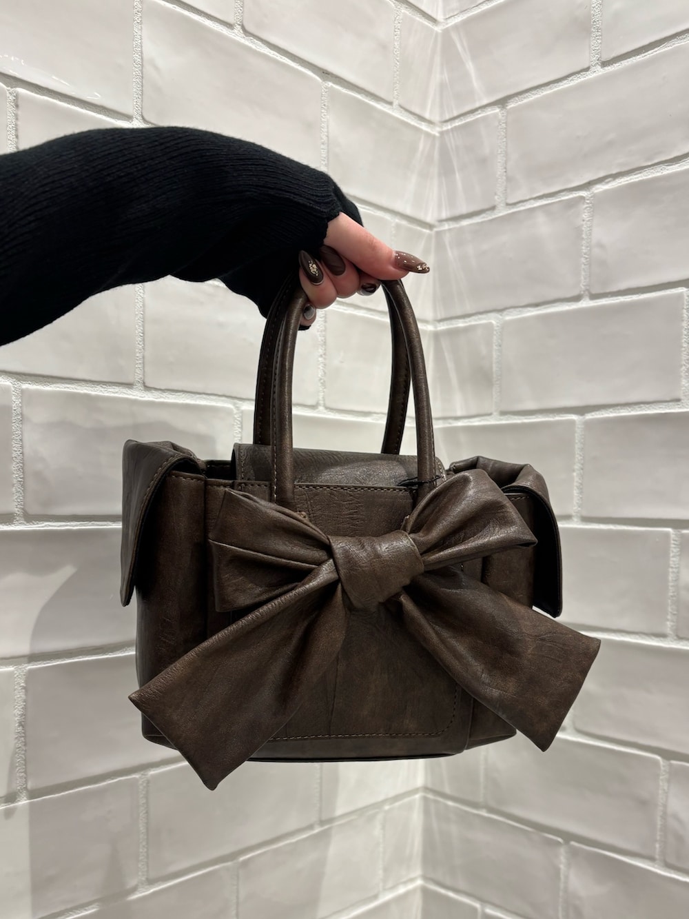 ブラック系のニット/セーター、ブルー系のデニムパンツ、ブラウン系のハンドバッグを着用したレディースの冬コーディネートの6枚目の写真