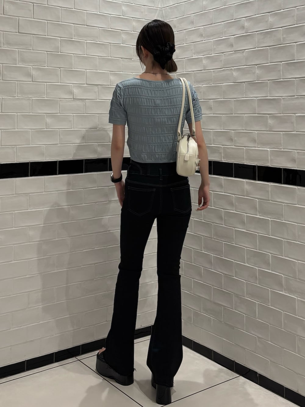 ブルー系のニット/セーター、ブラック系のデニムパンツ、ホワイト系のハンドバッグを着用したレディースの春コーディネートの3枚目の写真