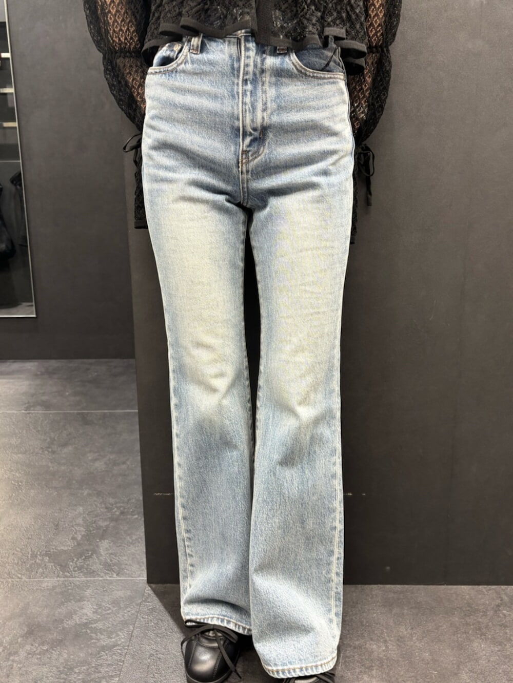 ブラック系のスニーカー、ブルー系のデニムパンツ、ブラック系のニット/セーターを着用したレディースの春コーディネートの5枚目の写真