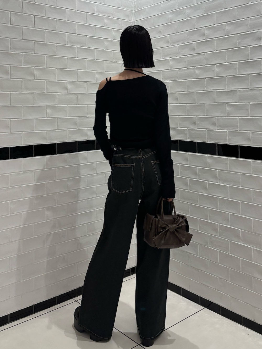 ブラック系のニット/セーター、ブルー系のデニムパンツ、ブラウン系のハンドバッグを着用したレディースの冬コーディネートの3枚目の写真