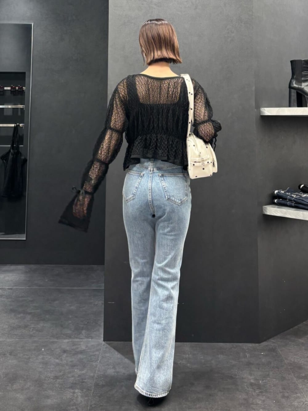 ブラック系のスニーカー、ブルー系のデニムパンツ、ブラック系のニット/セーターを着用したレディースの春コーディネートの3枚目の写真