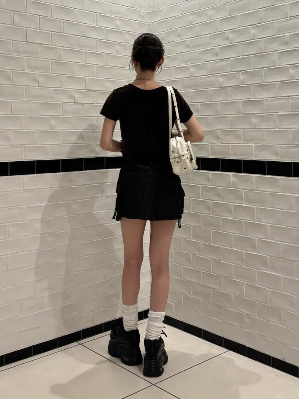 ホワイト系のショルダーバッグ、ブラウン系のTシャツ/カットソー、ブラック系のスニーカーを着用したレディースの夏コーディネートの3枚目の写真