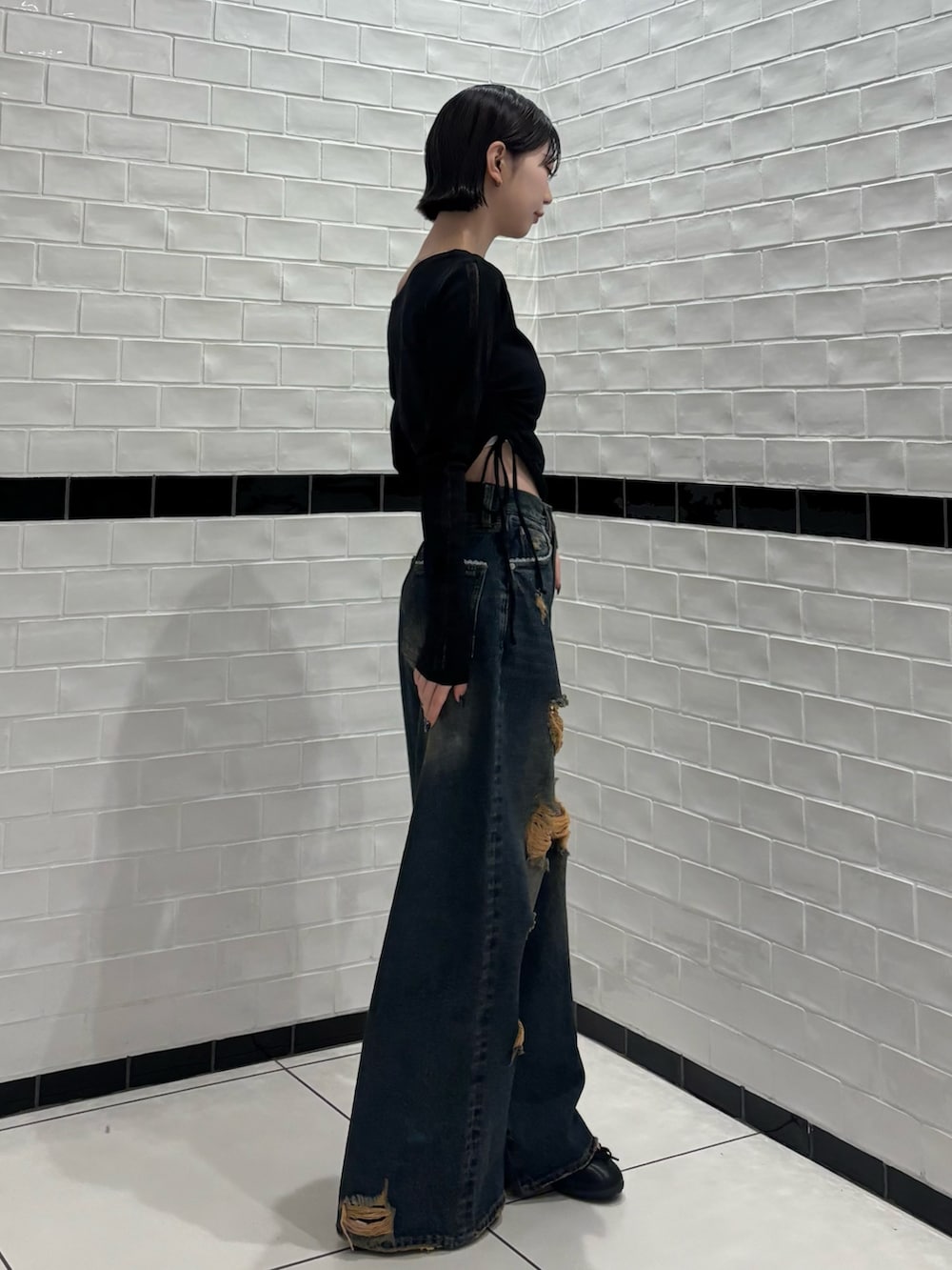 ブラック系のTシャツ/カットソー、ブルー系のデニムパンツ、ブラック系のスニーカーを着用したレディースの春コーディネートの2枚目の写真