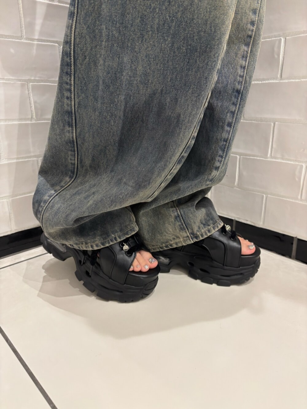 ホワイト系のショルダーバッグ、ブラック系のサンダル、ブルー系のデニムパンツを着用したレディースの夏コーディネートの6枚目の写真
