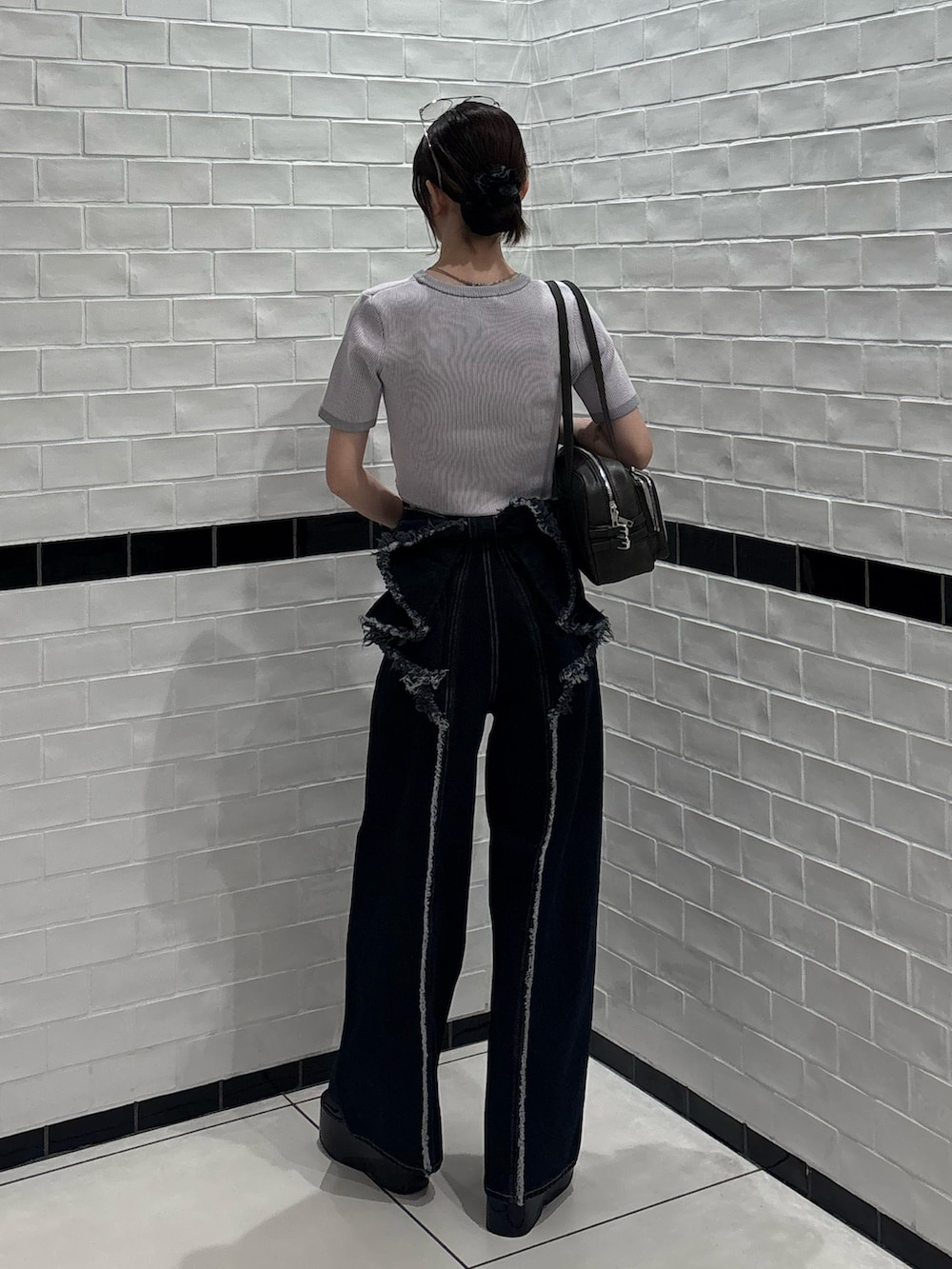 ピンク系のニット/セーター、ブルー系のデニムパンツ、ブラック系のショルダーバッグを着用したレディースの夏コーディネートの3枚目の写真