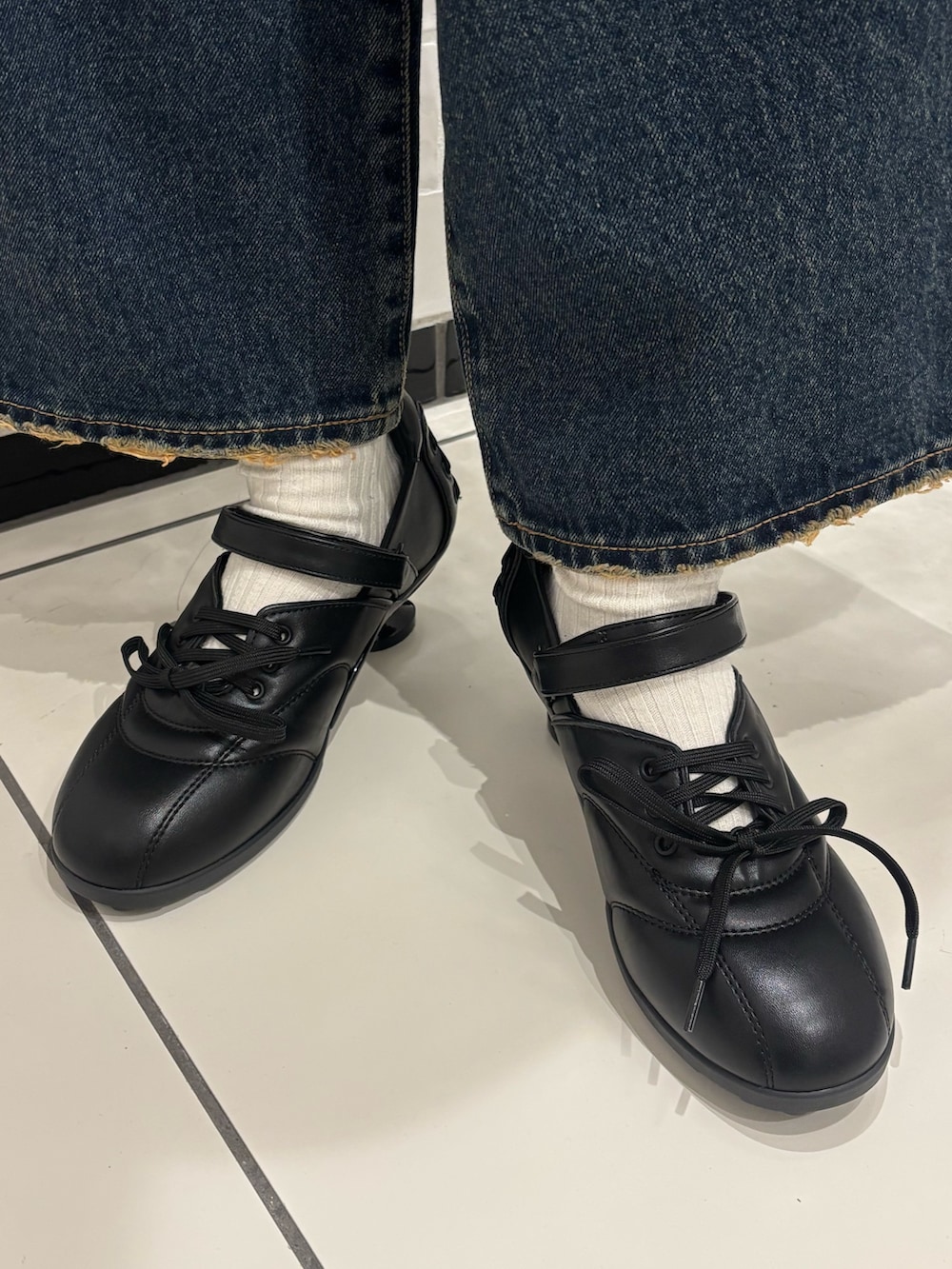 ブラック系のTシャツ/カットソー、ブルー系のデニムパンツ、ブラック系のスニーカーを着用したレディースの春コーディネートの6枚目の写真