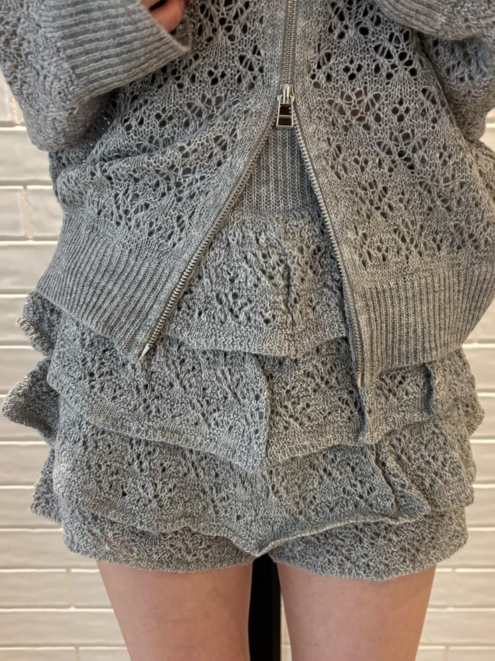 グレー系のパーカー、グレー系のスカート、ブラック系のサンダルを着用したレディースの春コーディネートの5枚目の写真