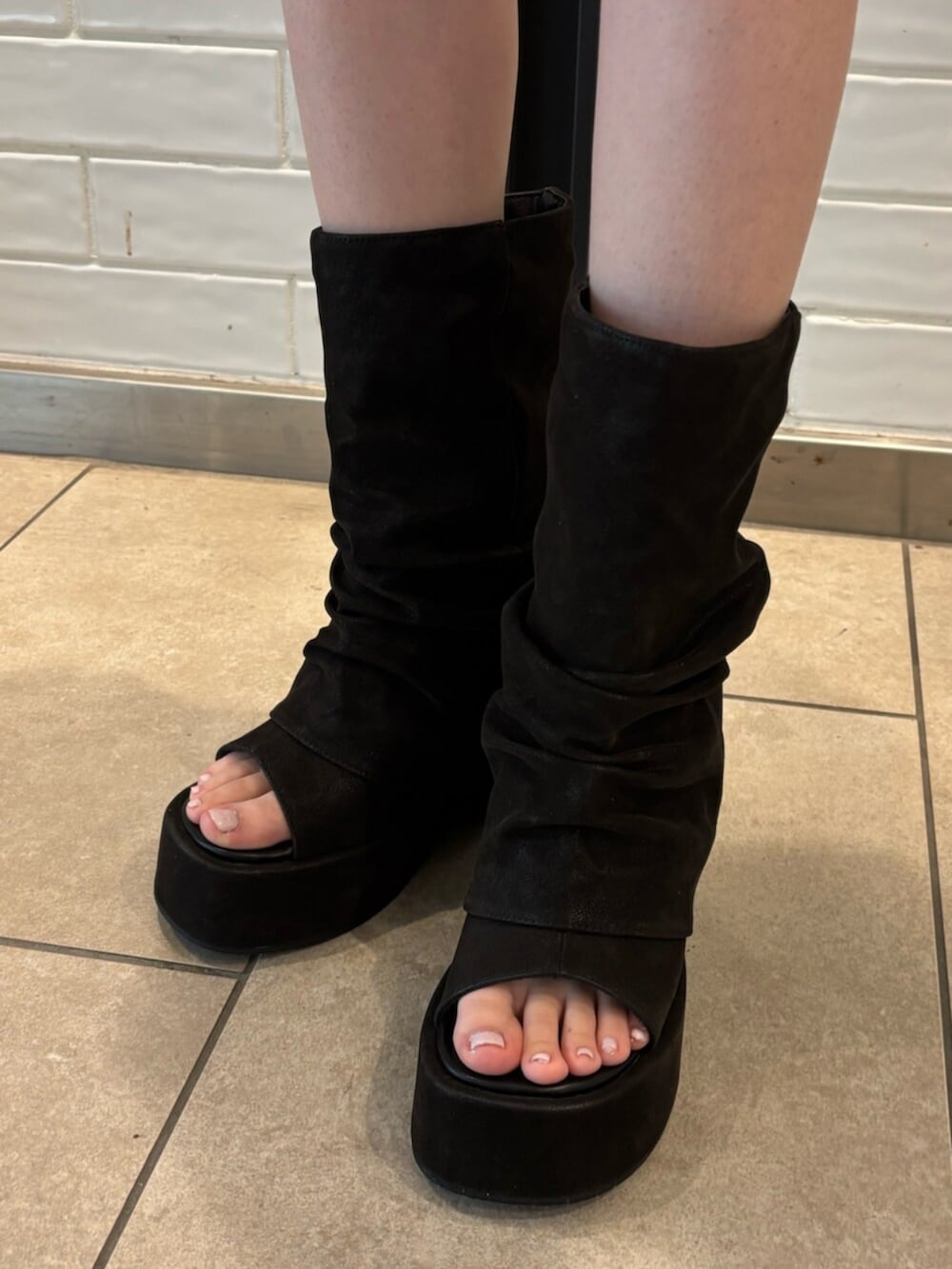 グレー系のパーカー、グレー系のスカート、ブラック系のサンダルを着用したレディースの春コーディネートの6枚目の写真